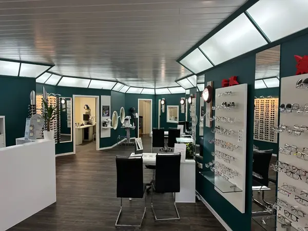 Modernes Optikergeschäft mit Brillenauswahl, Beratungstischen und stilvoller Einrichtung.